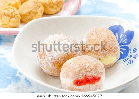 Fresh donuts with jam and eclair on dining table.