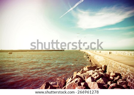 Coast and nature. Jetty at a sea and blue bright sky. Retro vintage instagram picture.