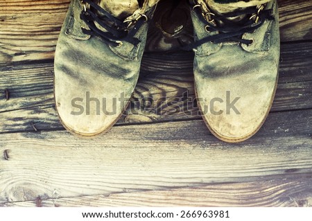 Old dirty boots with the untied laces on grunge a background. Old footwear.
