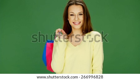 Happy attractive female shopper carrying her purchases in brightly colored carrier bags turning to smile over her shoulder at the camera