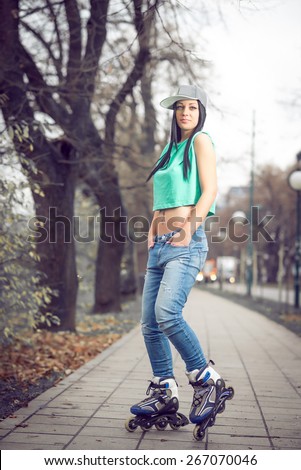 Young adult teenage girl doing roller skating in park during winter