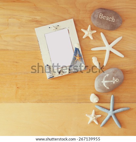 collection of nautical and beach objects creating a frame over wooden background, 