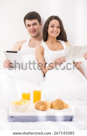 Smiling young couple having breakfast  in bed.