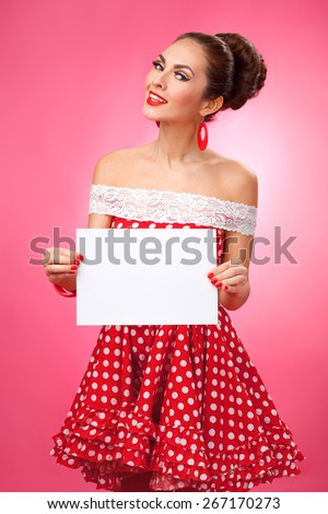 Portrait of a smiling cute young female model with blank sign in her arms wearing red dress