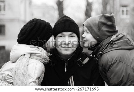 Children, a boy and a girl, kiss her dad on the cheek on the street in cold weather