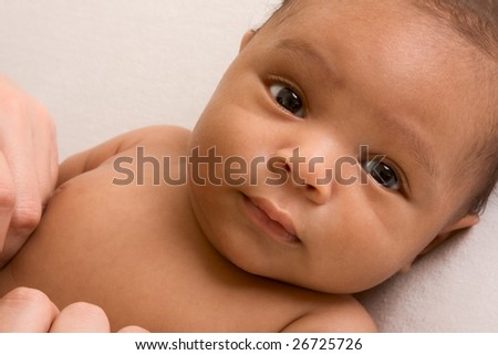 Thoughtful biracial mix of Hispanic and African American infant lying down on yellowish colored blanket Royalty-Free Stock Photo #26725726