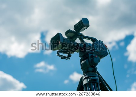 Professional video camera on a tripod against the blue sky