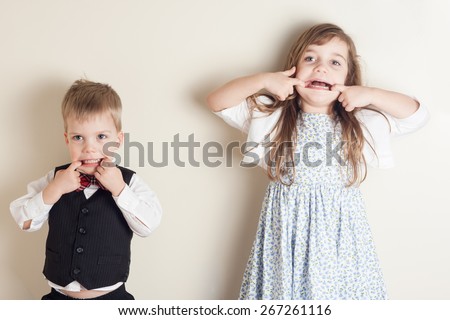 brother and sister standing against a wall and making faces