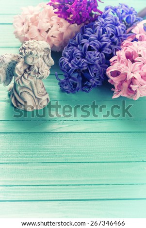 Background with angel and fresh pink, violet, blue hyacinths on painted wooden planks. Selective focus. Place for text. Toned image.
