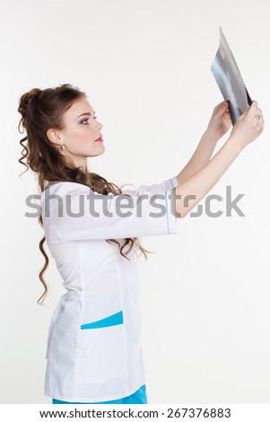 Young pretty girl intern looking at the x-ray picture of knee in hospital