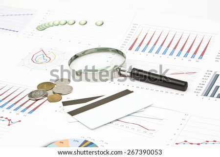 Business still-life of a diagram, magnifier, coins, credit card