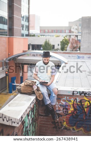 young handsome hipster gay modern man using tablet in town