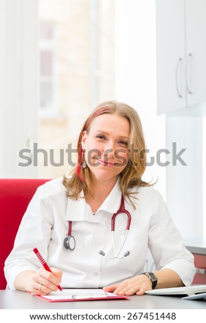 Young gynaecologist writing medical prescription in surgery at desk