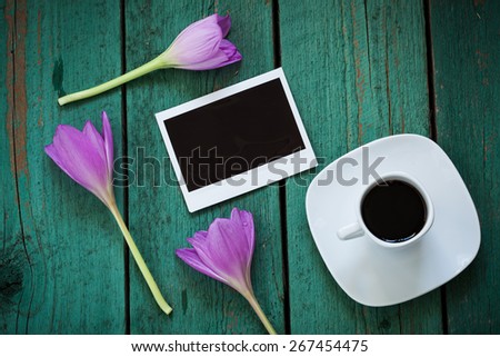 Empty photo card and a cup of coffee on old green wooden board, memory concept