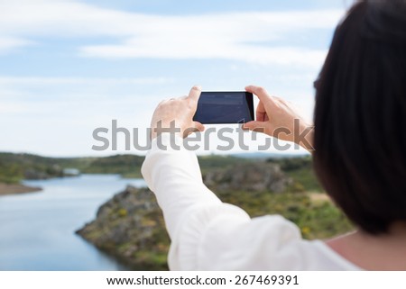 Back view of a woman taking photograph with a smart phone camera