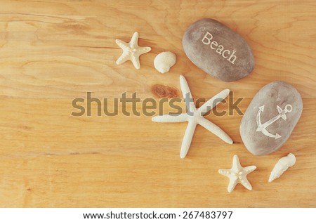 collection of nautical and beach objects creating a frame over wooden background,
