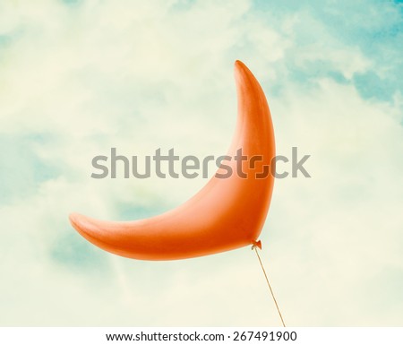Red Ramadan crescent balloon in vintage blue sky with clouds,