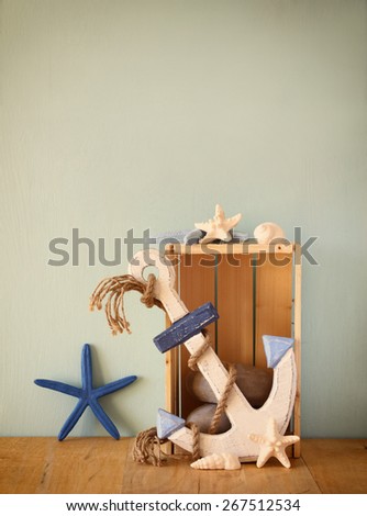 old nautical wood anchor and shells on wooden table over wooden aqua background
