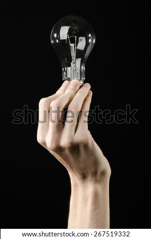 Energy consumption and energy saving topic: human hand holding a light bulb on black background in studio