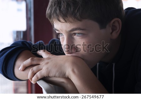 Pensive child looking through a window Royalty-Free Stock Photo #267549677