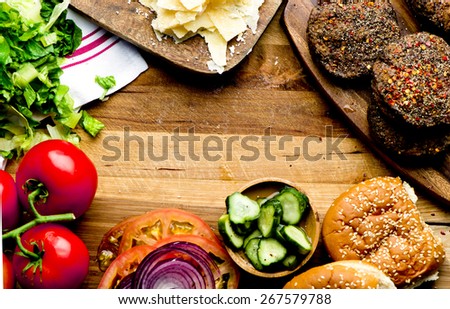 Cheeseburger. Burger ingredients a juicy beef patty, cheese, fresh lettuce, onion, tomato, pickles and a  fresh bun with sesame seeds presented on a wooden cutting board with copy space.