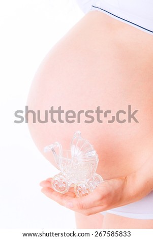 belly of a pregnant woman isolated on white, holding a toy stroller