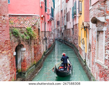 Venetian gondolier punting gondola through green canal waters of Venice Italy Royalty-Free Stock Photo #267588308