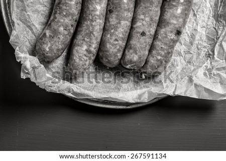 Raw sausage with on a dark wooden background in black and white
