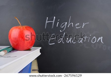 Classroom with red apple,books and handwriting in white chalk on blackboard