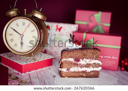 Picture close up on set of cake, alarm clock and gift decorations