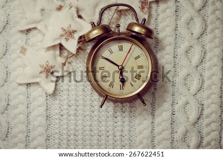 Picture of alarm clock on knitted background surrounded with decorative stars