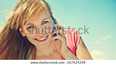 young smiling woman talking on mobile phone on blue sky background. girl with a smartphone