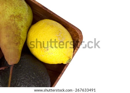 Lemon with avocado and pear in a wooden plate.
