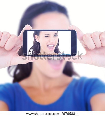 Pretty brunette winking at camera against hands holding smartphone