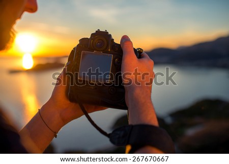 Man photographing with professional photo camera beautiful landscape on the sunset on the top of the mountain