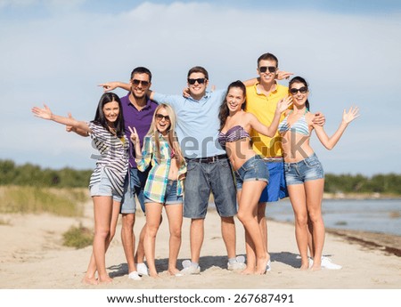 summer holidays, tourism, travel, gesture and people concept - group of happy friends in sunglasses waving hands on beach