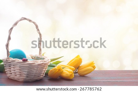 Beautiful Easter eggs in a basket. Delicate yellow spring tulips. Spring Easter holidays. Wooden board rustic. Beautiful light background