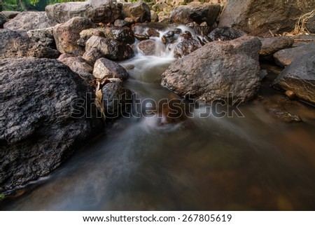 Waterfall cold fresh water stream long shutter speed blurred motion on black stone rocks in park