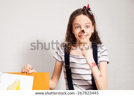 Cheerful child artist. Girl in classroom near easel