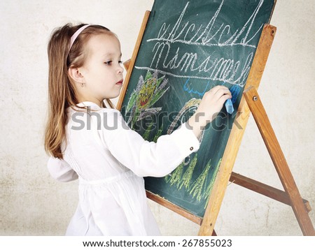 Little girl drawing a picture with chalk on the blackboard