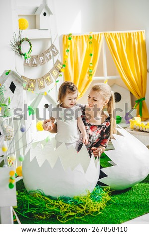 baby sitting in a big egg with  mother on the grass, Easter decoration