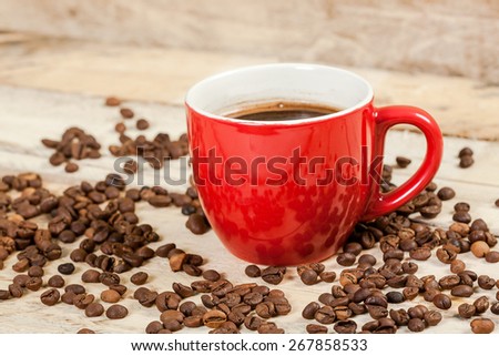 Cup of coffee on a wooden table with coffee beans.