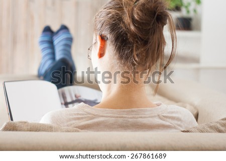 Young  woman reading magazine book relaxed in sofa Royalty-Free Stock Photo #267861689