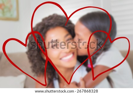 hearts against pretty mother sitting on the couch with her daughter smiling at camera