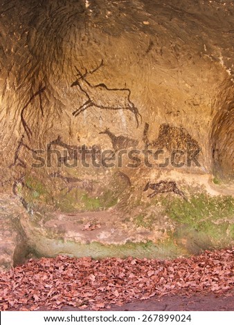Black carbon paint of human hunting on sandstone wall, copy of prehistoric picture. Abstract children art in sandstone cave