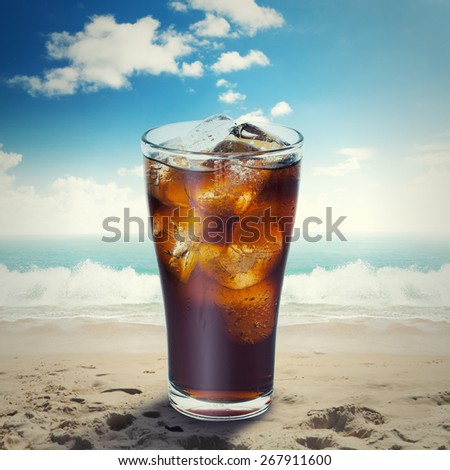 cola glass with ice on the beach