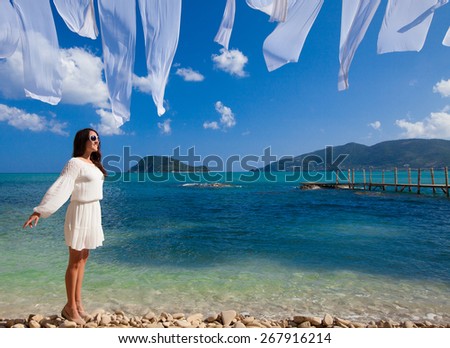 Happy woman in summer white dress on beach. Caucasian girl relaxing and enjoying peace on vacation.
