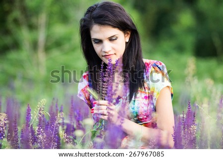 Beautiful girl posing in the park with wild flowers. Image has grain texture visible on maximum size
