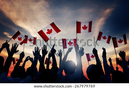 Silhouettes of People Holding Flag of Canada Royalty-Free Stock Photo #267979769