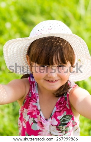 Beautiful little cute having fun outdoors in her summer hat.